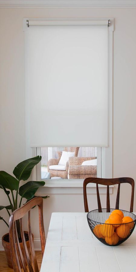White window shade pulled down halfway over a window in a dining area