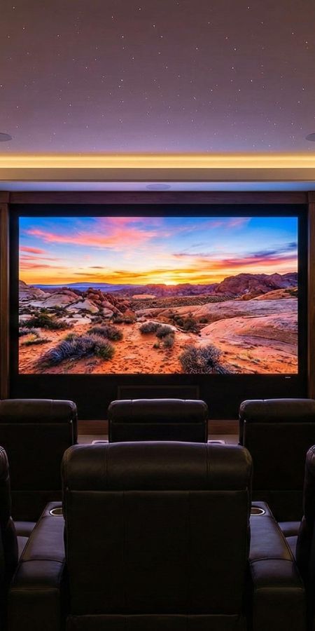 Home theater room with leather seating and a large projection screen displaying a desert landscape