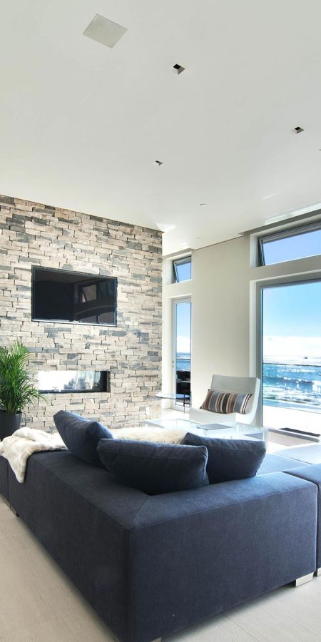 Living room with a modern fireplace facing large glass doors opening to the ocean